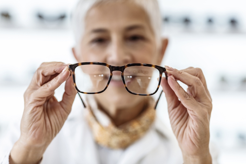 Older woman holding up glasses