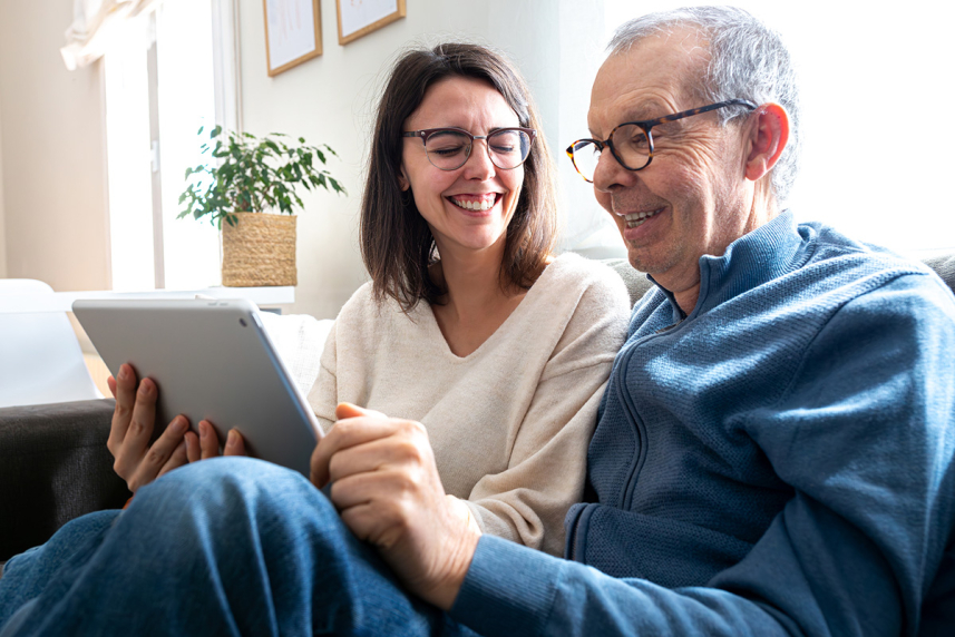Father and adult daughter looking at a tablet