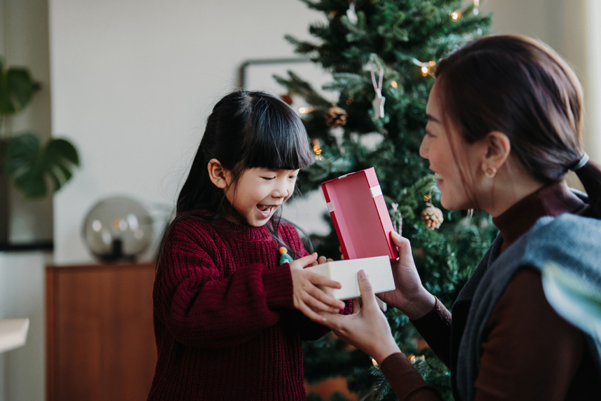 Kid opening gift with her mother