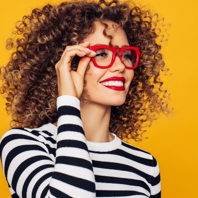 A smiling woman holding her new frames