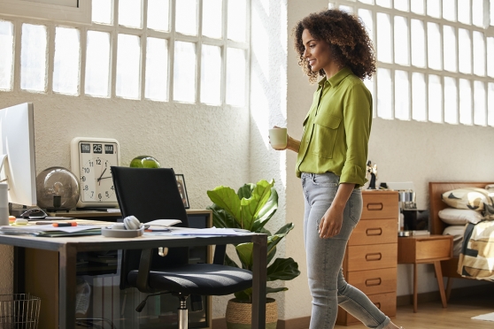 Person approaching a desk with a cup coffee