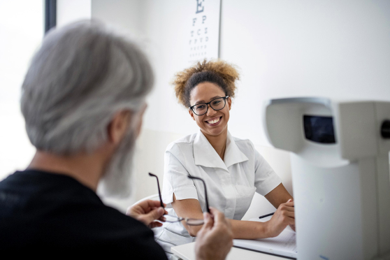 smiling eye care provider and man cleaning glasses