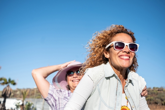 Two adult women smiling about getting an eye exam for their prescription sunglasses 