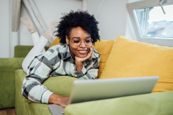 Woman laying on couch using a laptop